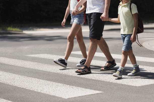 padre de la mano con sus hijos mientras que en el cruce peatonal - crossing zebra crossing crosswalk street fotografías e imágenes de stock