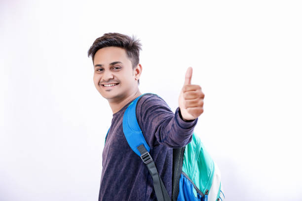 バッグを持つインドの大学少年 - thumbs up book smiling student ストックフォトと画像