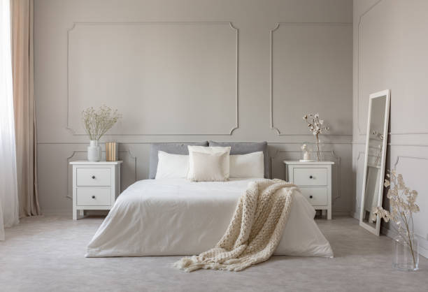 istock Flowers on nightstand table in delightful bedroom interior with grey and white design 1149261480