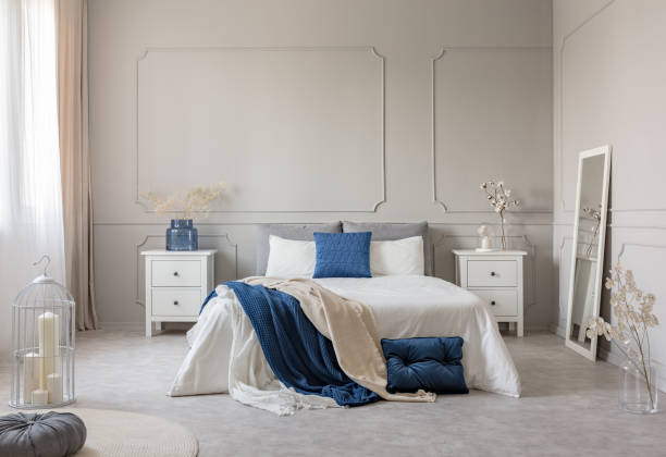 istock Blue pillow and blanket on white bed in spacious bedroom interior, copy space on empty grey wall 1149261662