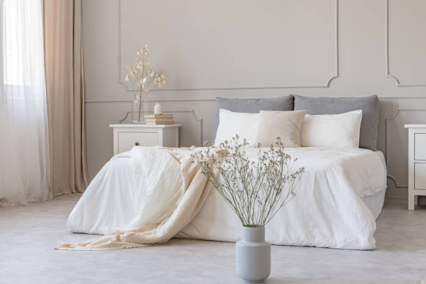 istock White flowers in vase in elegant grey bedroom interior with simple bedding 1149261799