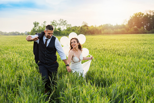 Couple just married celebrate their love, running through wheat field