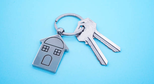 key chain with house symbol and keys on blue background,real estate concept - key real estate key ring house key imagens e fotografias de stock