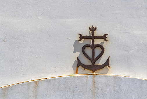 rusty Cross of the Camargue on a white wall