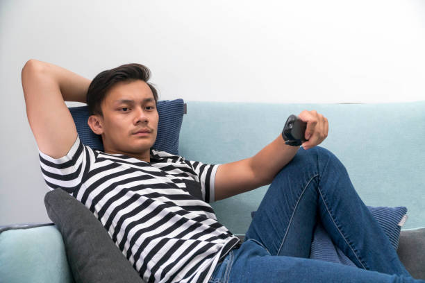 istock Young Malay man at the Sofa watching tv relaxing 1149267154