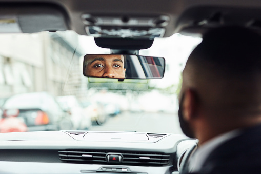 Cropped shot of a man looking into his rearview mirror while driving