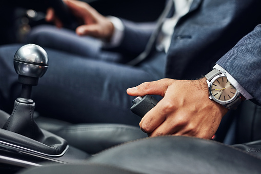 Closeup shot of a driver holding on to the handbrake lever of a motor vehicle