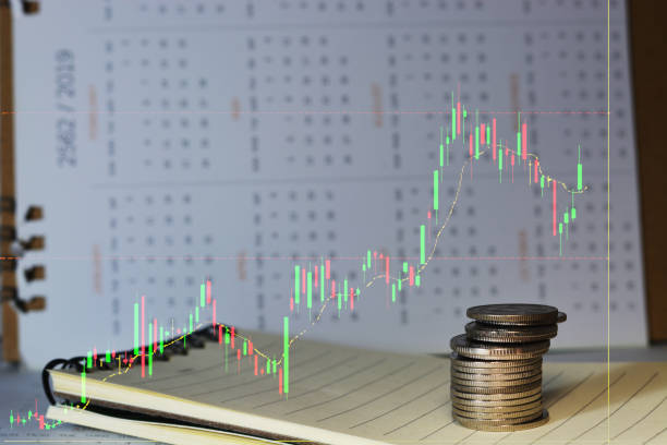 Coins stacks with financial graph on notebook, calendar background