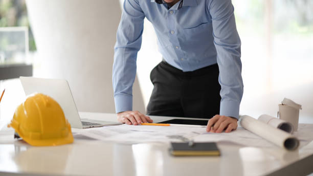 istock Young engineer or architect working with blueprints and laptop in office 1149269787