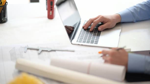 istock Young engineer or architect working with blueprints and laptop in office 1149270824