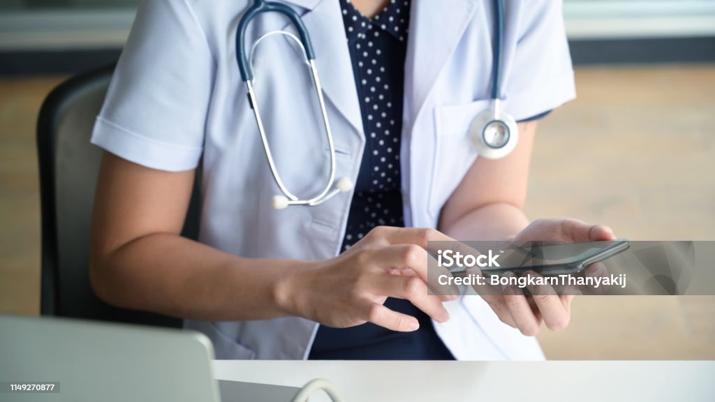 Cropped image of female doctor texting and using on smartphone Mobile Phone Stock Photo