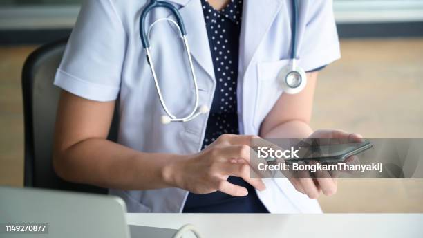 Cropped Image Of Female Doctor Texting And Using On Smartphone Stock Photo - Download Image Now