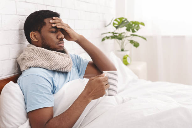 istock Sick african-american man drinking hot healing tea in bed 1149271136