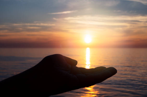 istock Man's hand cradling a sunset at sea 1149273607