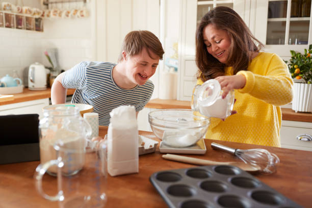 young downs síndrome de hornear en la cocina en el hogar - disabled adult fotografías e imágenes de stock