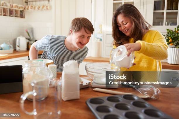 Young Downs Syndrome Couple Baking In Kitchen At Home Stock Photo - Download Image Now
