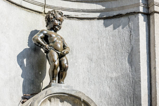 Manneken Pis fountain in the historic center of Brussels, Belgium. Manneken Pis is a historic fountain in the old town of Brussels, Belgium, made of a bronze statue by sculptor Jerome Duquesnoy the Elder, depicting a jovial, naked little boy standing and urinating. manneken pis statue in brussels belgium stock pictures, royalty-free photos & images