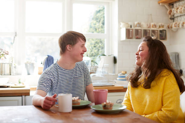 Young Downs Syndrome Couple Enjoying Tea And Cake In Kitchen At Home Young Downs Syndrome Couple Enjoying Tea And Cake In Kitchen At Home Mentally stock pictures, royalty-free photos & images