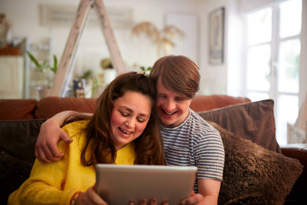 istock Loving Young Downs Syndrome Couple Sitting On Sofa Using Digital Tablet At Home 1149277312