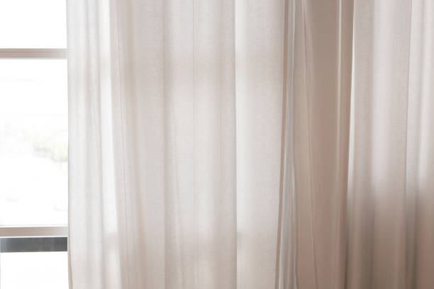 The white curtains stuck at the window, in a close-up view.