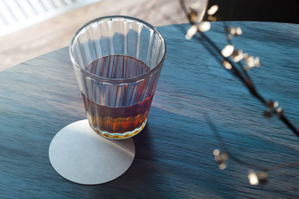 Transparent glass with tea and beer coaster on wooden table. 3d rendering. stock photo