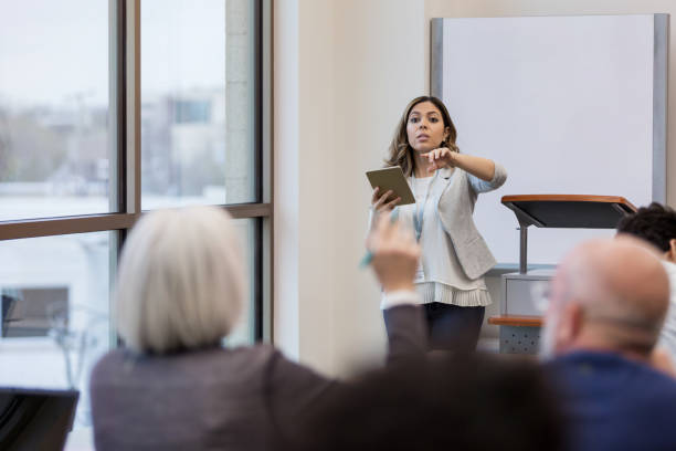 istock Mid adult education teacher points to student 1149285519