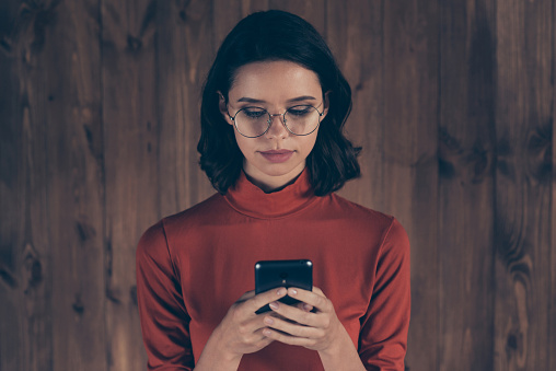 Close up photo serious focused boss chairman use user modern technology device read search news information brunette hair hairstyle dressed modern specs red trendy stylish style pullover industrial.
