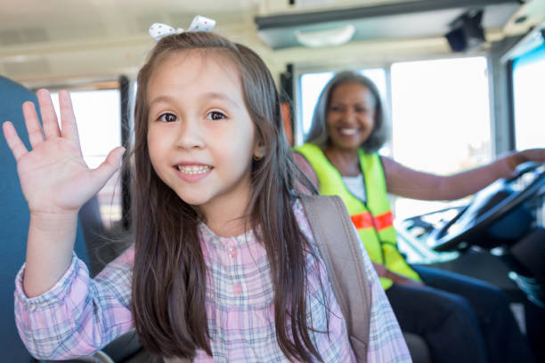 istock Young Hispanic girl waves while bus driver waits 1149286820
