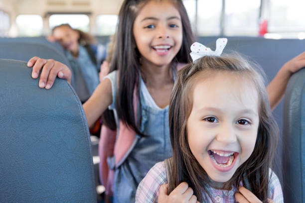 istock Elementary girls smile and laugh as they get on bus 1149286833