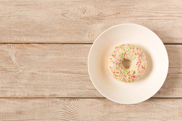 istock Fresh glazed donut with colorful sprinkles on a white plate. 1149292572