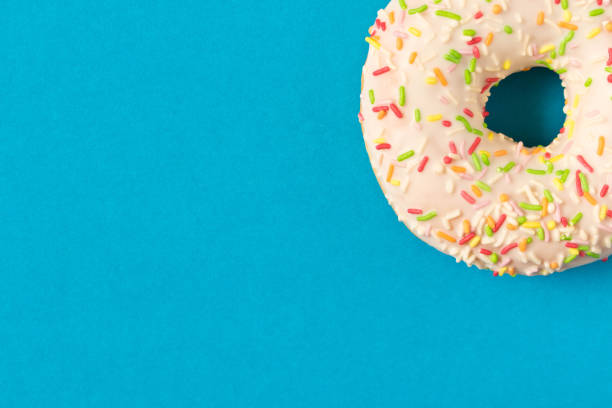 istock Fresh glazed donut with colorful sprinkles on a blue background. 1149293328