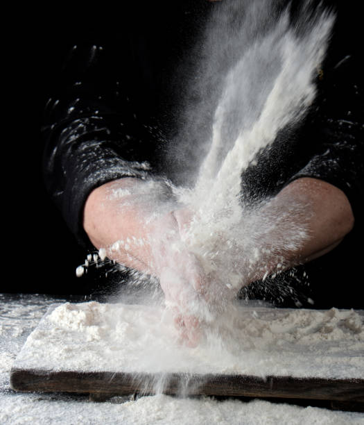 istock chef in black uniform sprinkles white wheat flour in different directions 1149293731