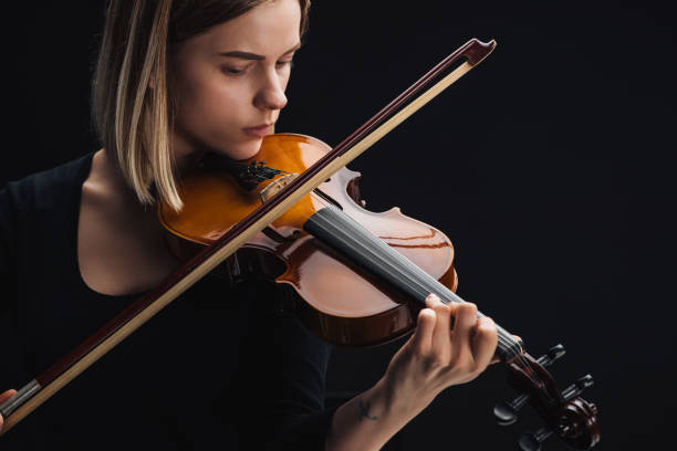 istock young concentrated woman playing cello with bow isolated on black 1149294657