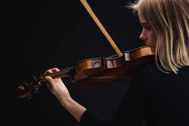 istock young concentrated woman playing cello with bow isolated on black with copy space 1149294658