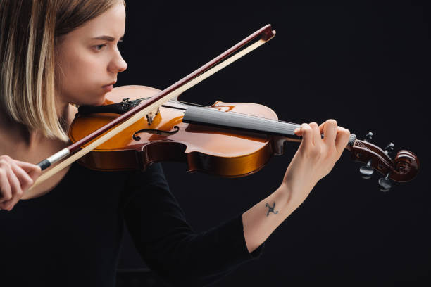 istock young tattooed woman playing cello with bow isolated on black 1149294664