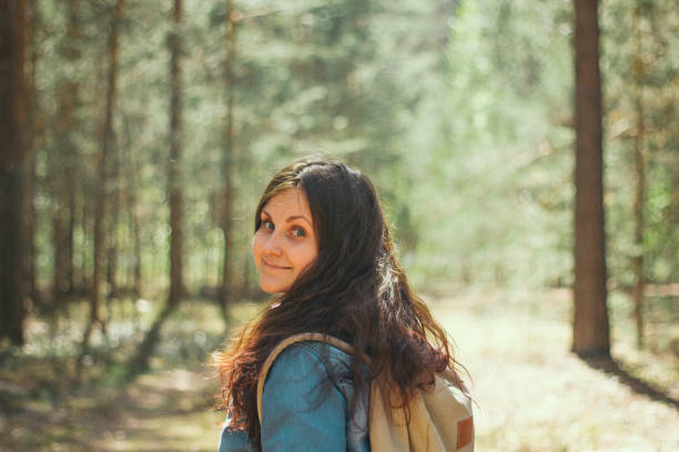 istock woman with backpack and denim jacket stands  in the woods 1149294732