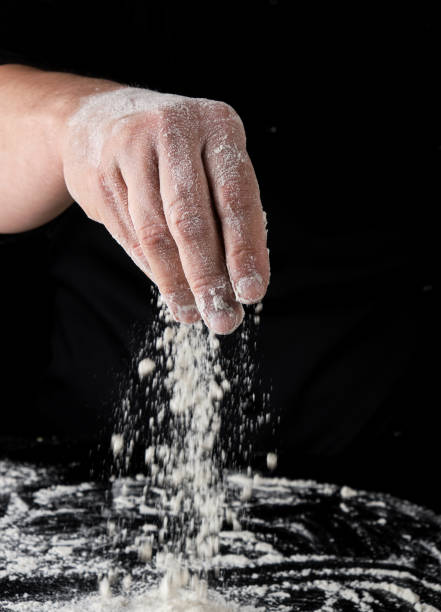 istock chef in black uniform sifts through his fingers white wheat flour 1149296740