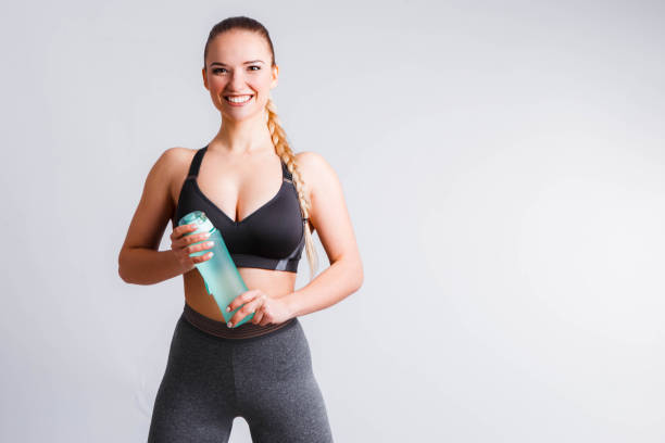 istock Beautiful athletic girl with a blue shaker on a light gray background. 1149298088