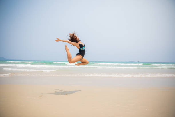 istock Female Gymnast Jumping on the beach 1149299072