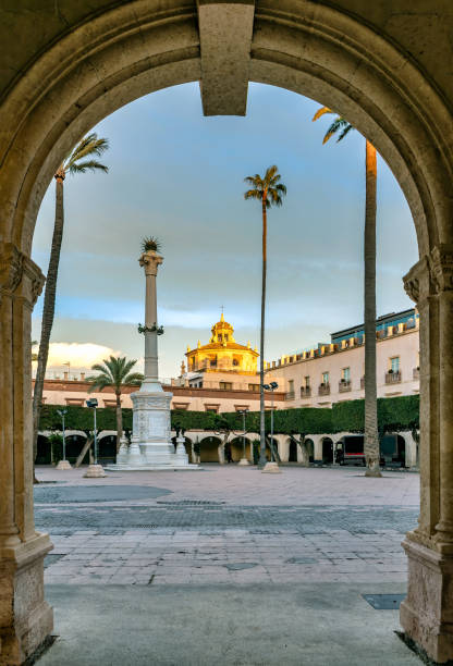 View of entrance to Plaza Vieja in downtown Almeria, Spain. View of entrance to historic Plaza Vieja in downtown Almeria, Spain, at dusk, with church’s roof still illuminated by the sunset light. almeria stock pictures, royalty-free photos & images