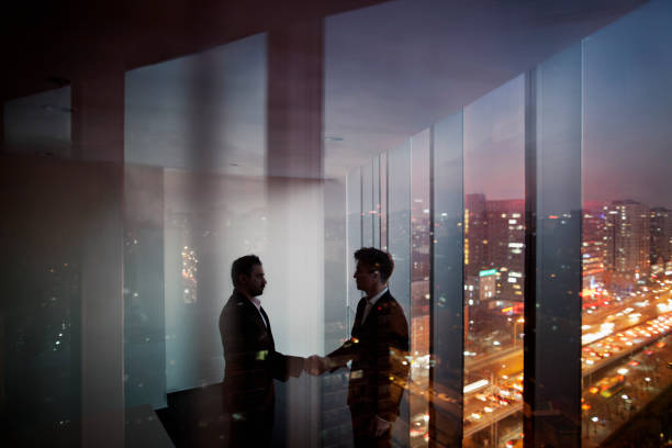 istock Businessmen shaking hands in office at night 1149306853