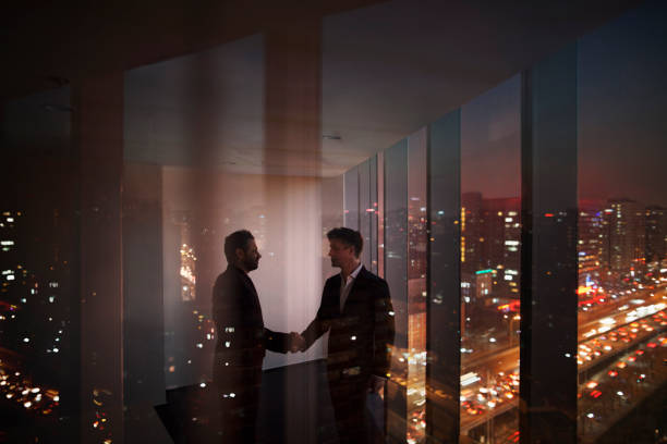 istock Businessmen shaking hands in office at night 1149306900