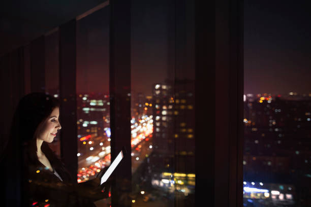 istock Businesswoman looking at tablet computer in office at night 1149306914