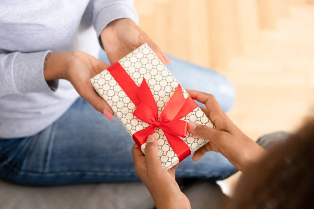 close up african american teen girl presenting gift to mother - mother gift imagens e fotografias de stock