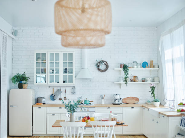 Wide shot of bright cosy domestic kitchen with white furniture and brick wall. Breakfast served on dining table Wide shot of bright cosy domestic kitchen with white furniture and brick wall. Breakfast served on dining table wide shot stock pictures, royalty-free photos & images