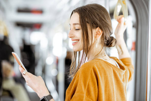 femme avec le téléphone au transport public - beautiful communication enjoyment happiness photos et images de collection