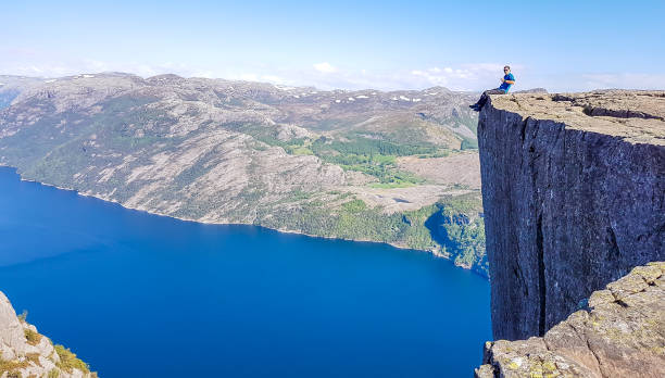 istock Norway - Boy sitting on a steep cliff with the view on Lysefjorden 1149317385