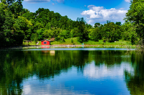 istock Local swimming pond with a red change house and clouds refelcted in water 1149317414