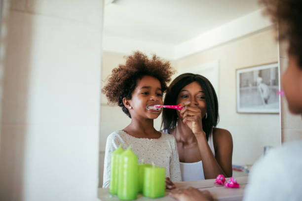 This will keep your teeth healthy Photo of african american mother and daughter brushing teeth in the morning. brushing teeth stock pictures, royalty-free photos & images