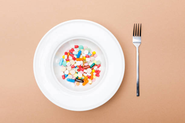 istock Top view of bowl with pills and fork on brown surface 1149323864